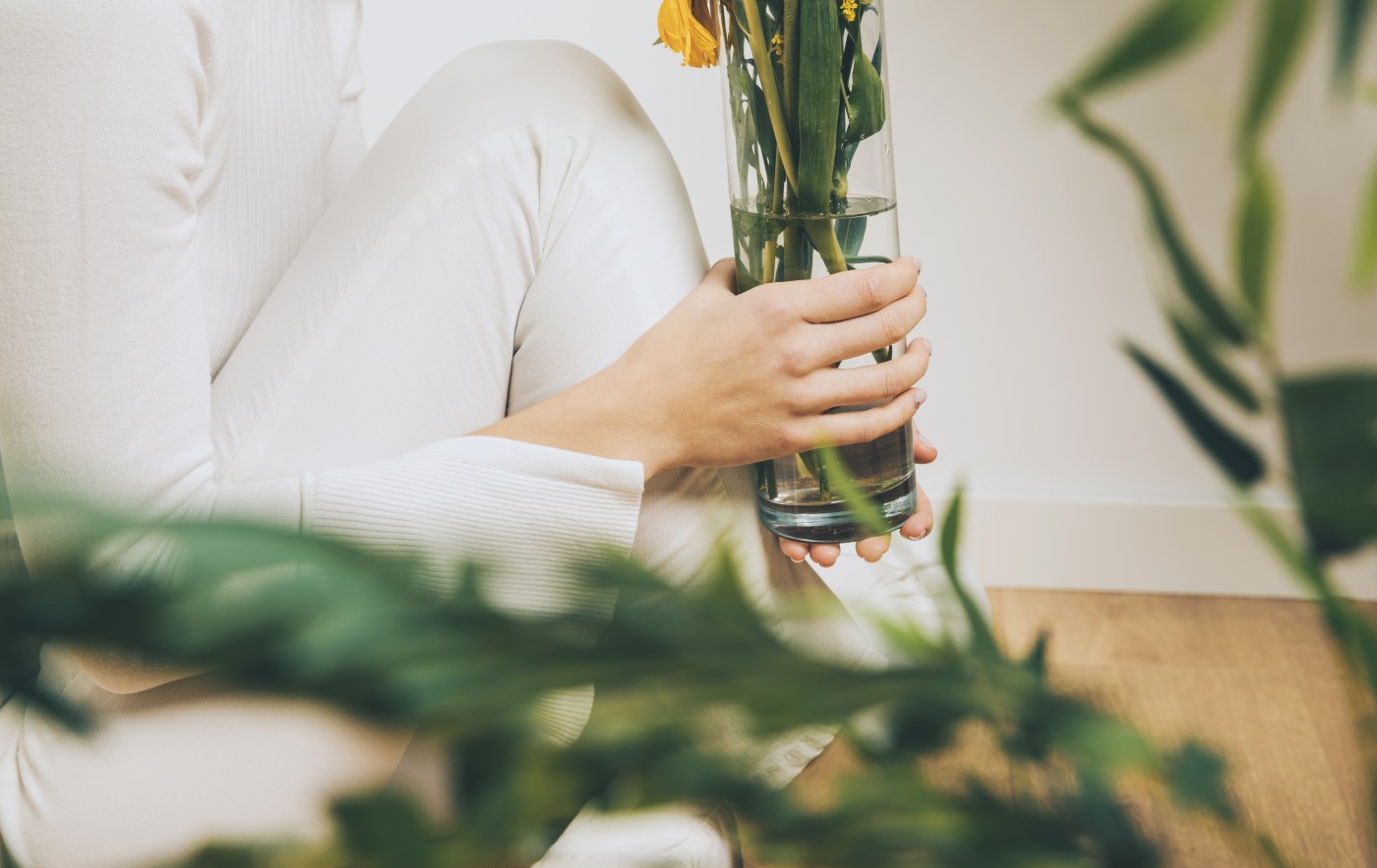 Femme installée au calme dans un intérieur fleuri